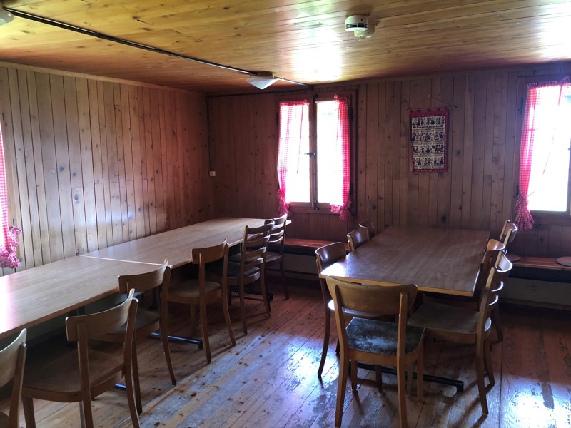 The wood-panelled dining room with long tables and red-checked curtains