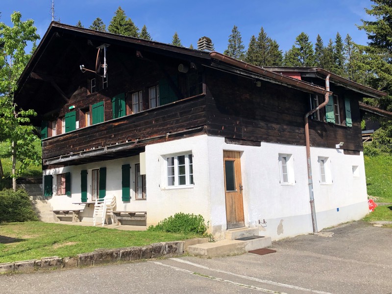 The Chilchmoos chalet, dark timber and green shutters, with a picnic table by the door